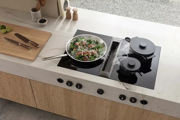 Aufsicht: Schwarzes BORA Induktionskochfeld in heller Marmorplatte. Dampf aus einer Pfanne wird in den rechteckigen Abzug gesaugt.